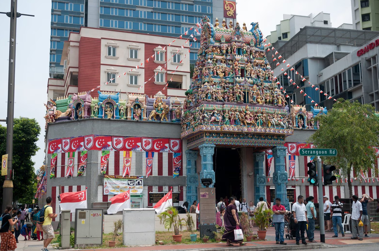 Wisatawan berjalan di Little India Singapura dengan latar bangunan warna-warni dan suasana budaya India yang ramai dan ramah Muslim.