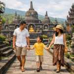Keluarga dengan satu anak sedang berjalan santai di area Brahmavihara Arama, Bali Utara, dengan latar belakang stupa dan arsitektur pura Buddha dalam suasana hijau dan damai