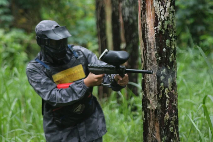 pria sedang menargetkan musuh di batu paintball