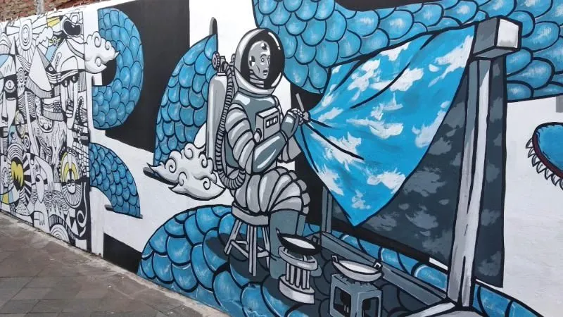 mural bergambar astronot sedang membatik di gang mural kampung taman jogja