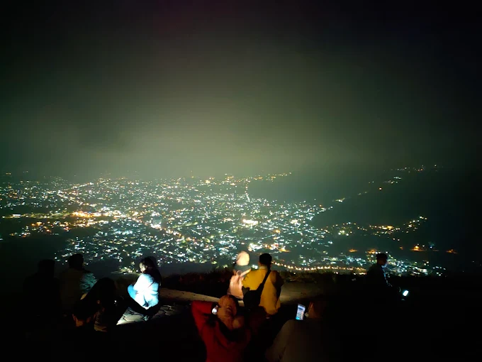 paralayang batu dengan pemandangan city light saat malam hari