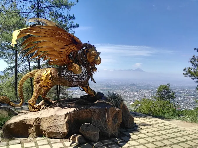 taman langit gunung banyak batu malang patung singa terbang dengan pemandangan kota