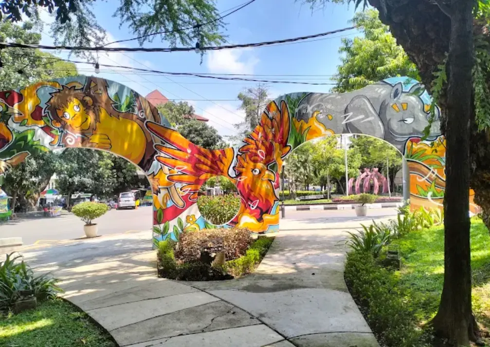 Taman Indonesia Kaya, tampak gerbang bergambar burung, badak, dan monyet. ada ruang terbuka hijau yang sejuk