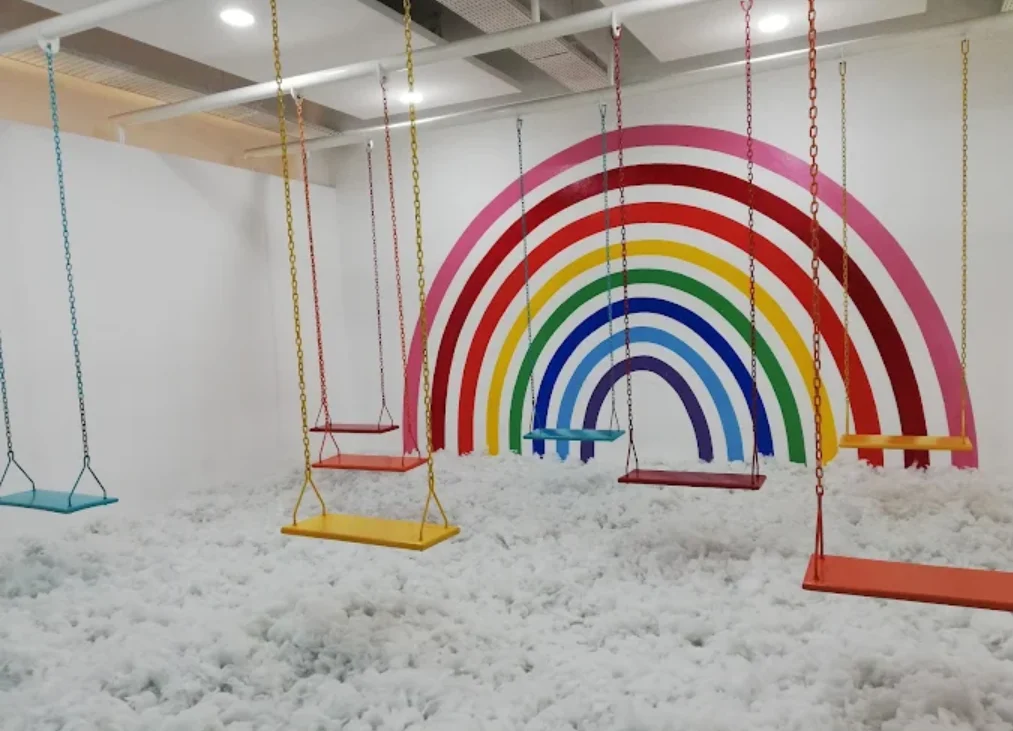 moja museum, museum seni. tampak beberapa ayunan warna warni di kolam bola dengan latar belakang pelangi
