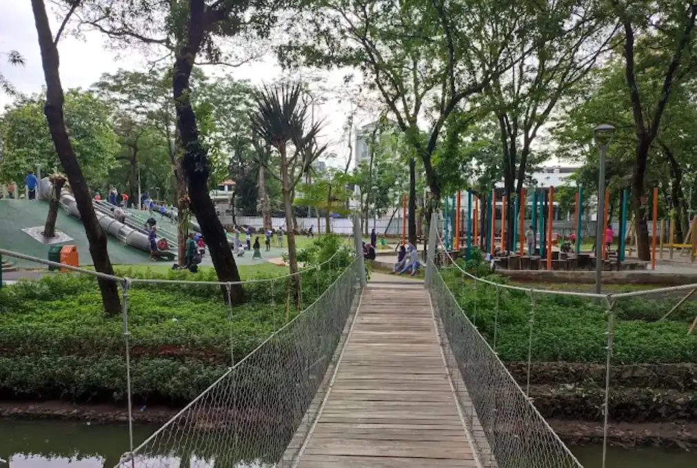 Tebet Eco Park. terlihat banyak orang sedang menimati taman kota ini. ada yang bermain perosotan, dan ada yang sedang duduk santai.