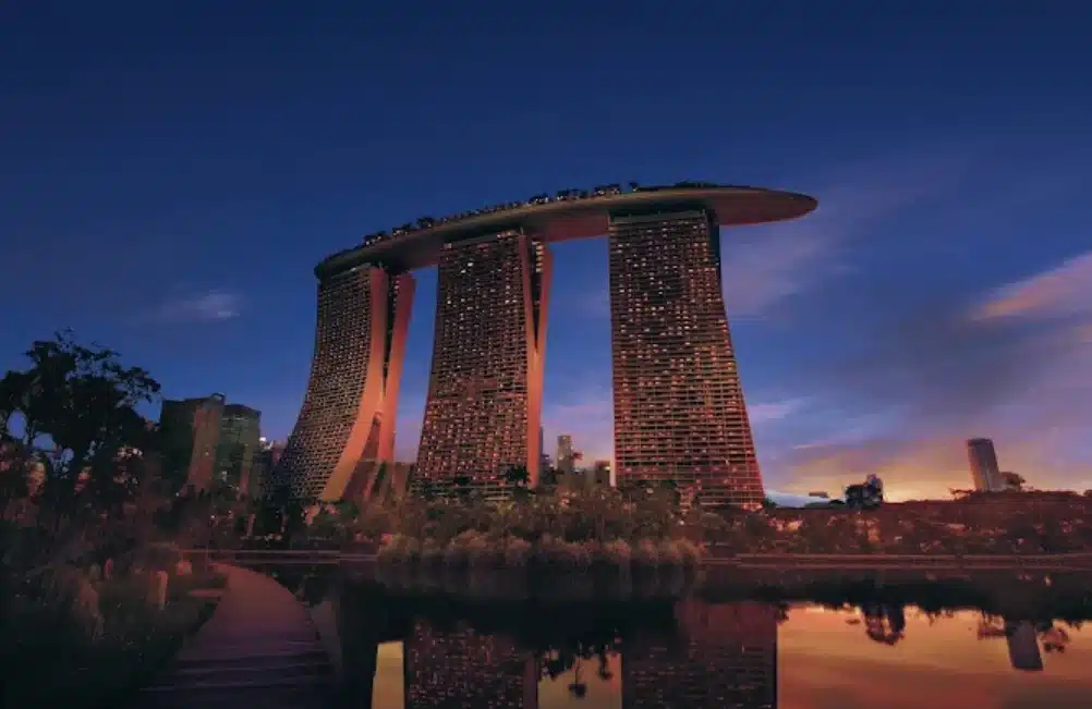 Pemandangan Marina Bay Sands di Singapura saat senja dengan refleksi gedung di permukaan air.